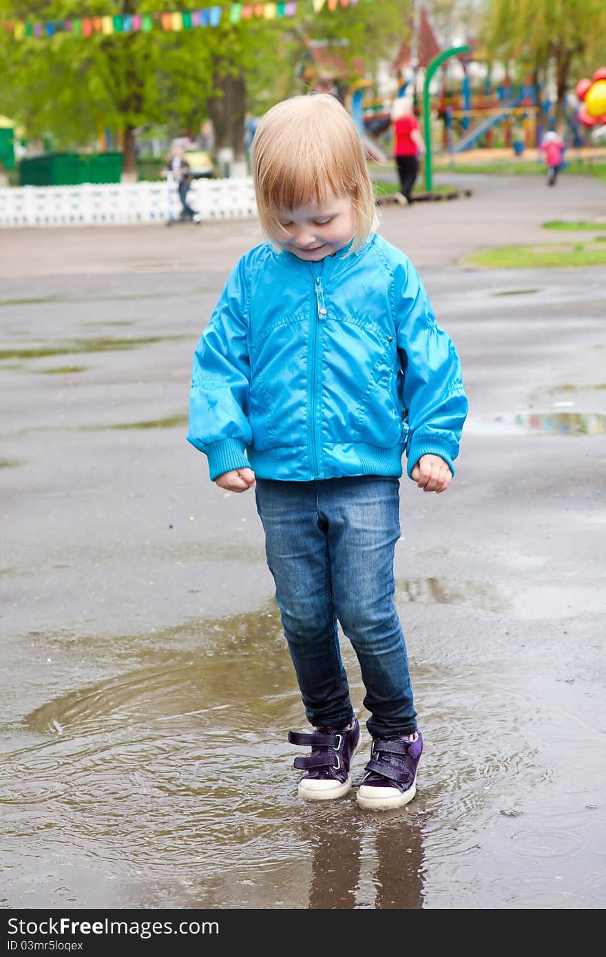 A girl is jumping in the puddle