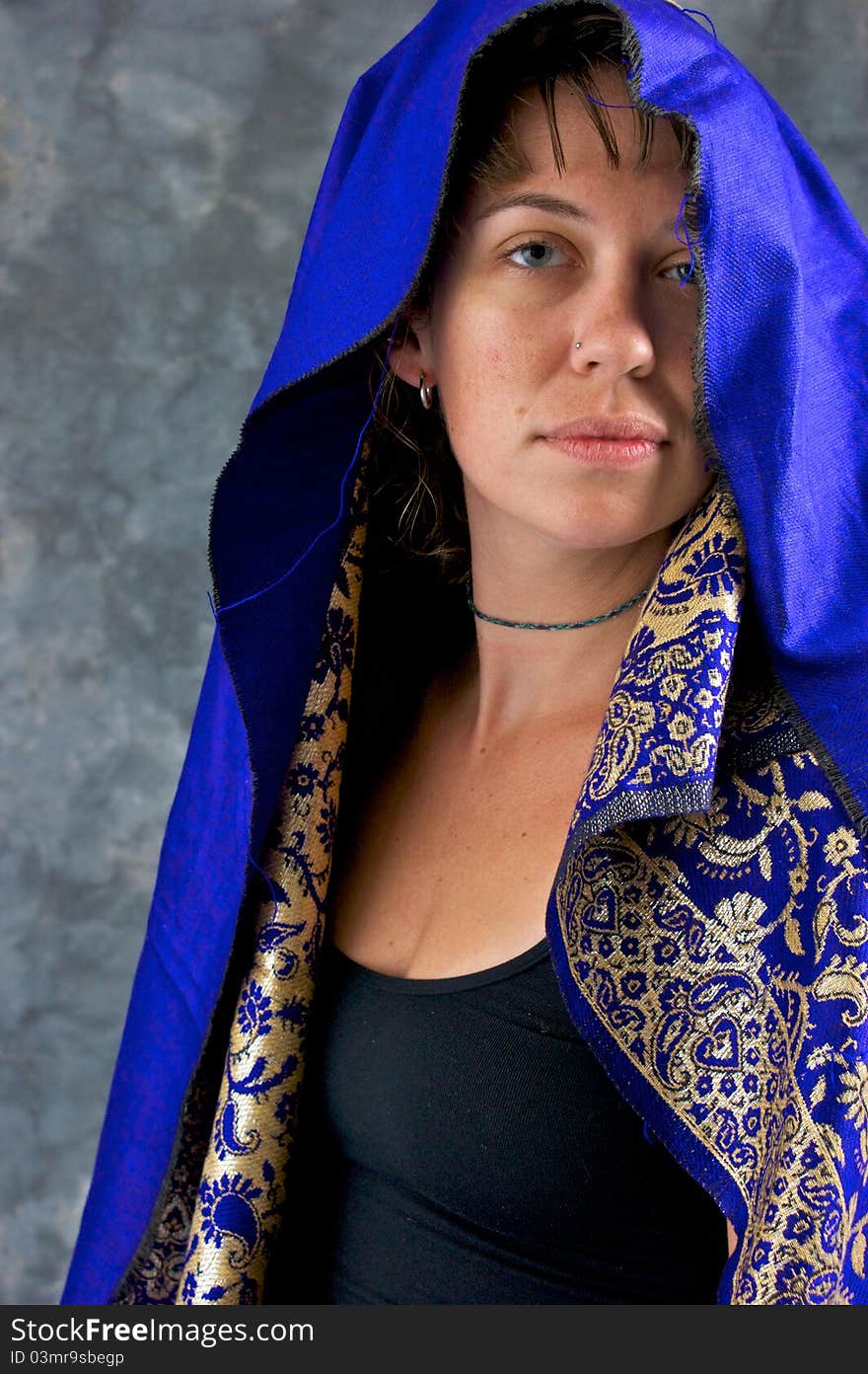 Portrait of a beautiful mystical woman looking at viewer her head is covered with blue hood. Portrait of a beautiful mystical woman looking at viewer her head is covered with blue hood.