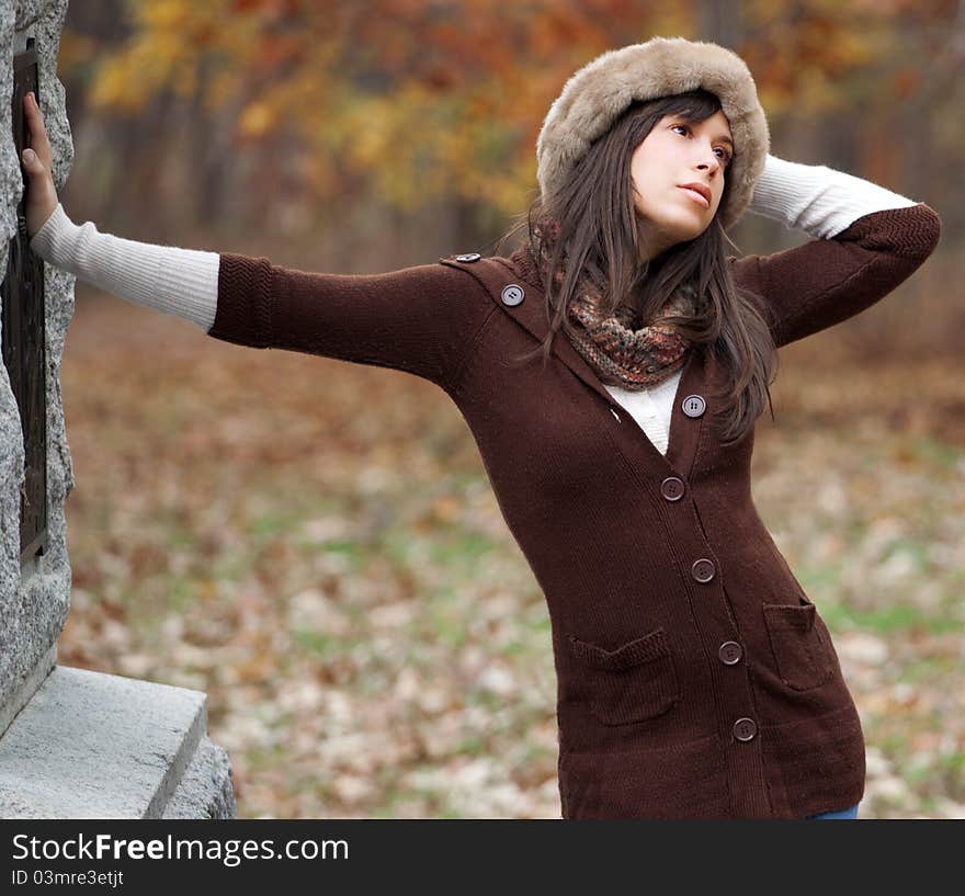 A portrait of a beautiful young woman, standing outdoors in fall in warm clothing, with brilliantly colored leaves behind her. A portrait of a beautiful young woman, standing outdoors in fall in warm clothing, with brilliantly colored leaves behind her