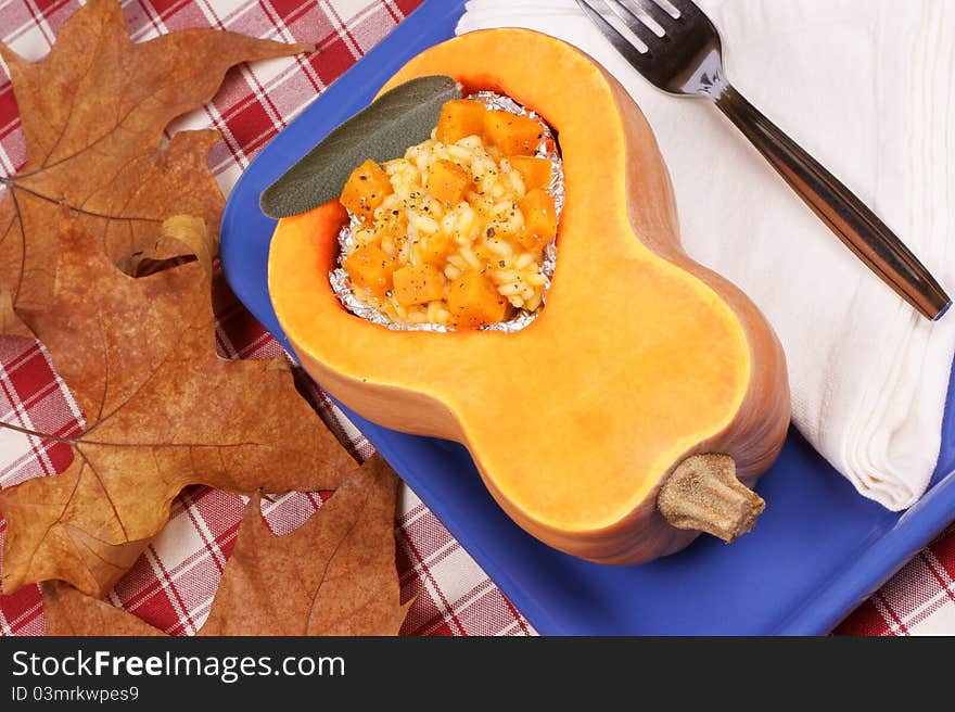 Half pumpkin filled with pumpkin risotto served on a blue plate. Half pumpkin filled with pumpkin risotto served on a blue plate