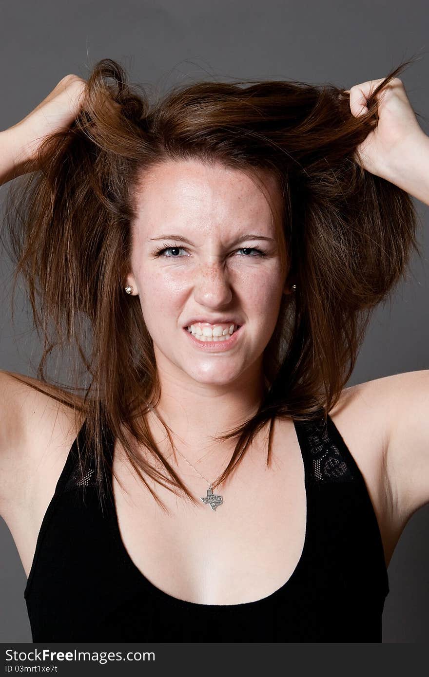 Caucasian female expresses her frustration by pulling at her hair in the studio. Caucasian female expresses her frustration by pulling at her hair in the studio