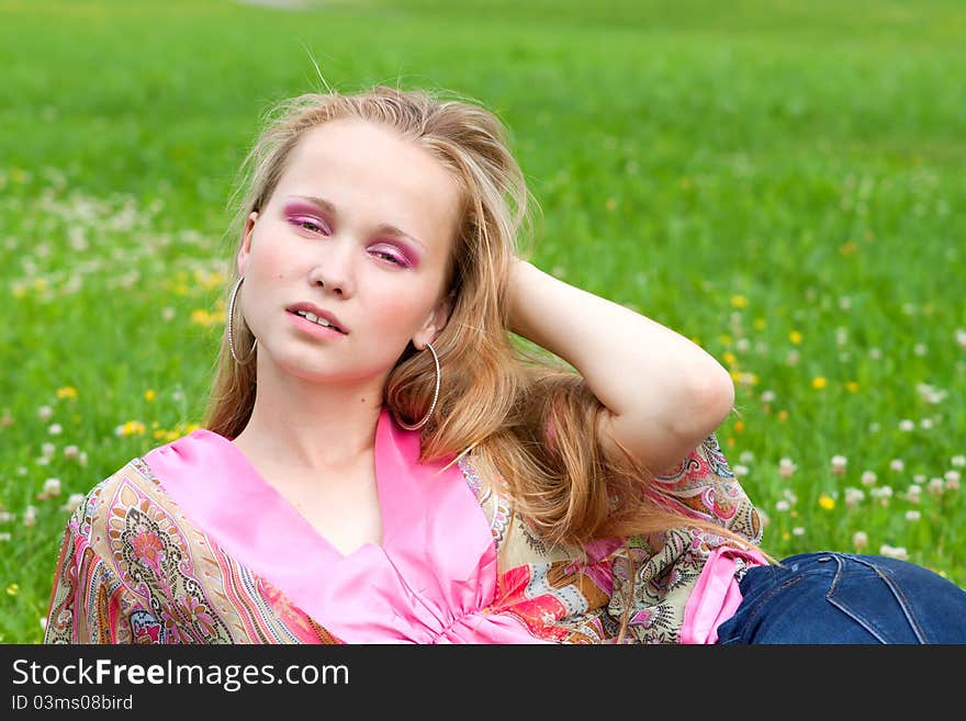 Portrait of a beautiful young woman on the grass in summer