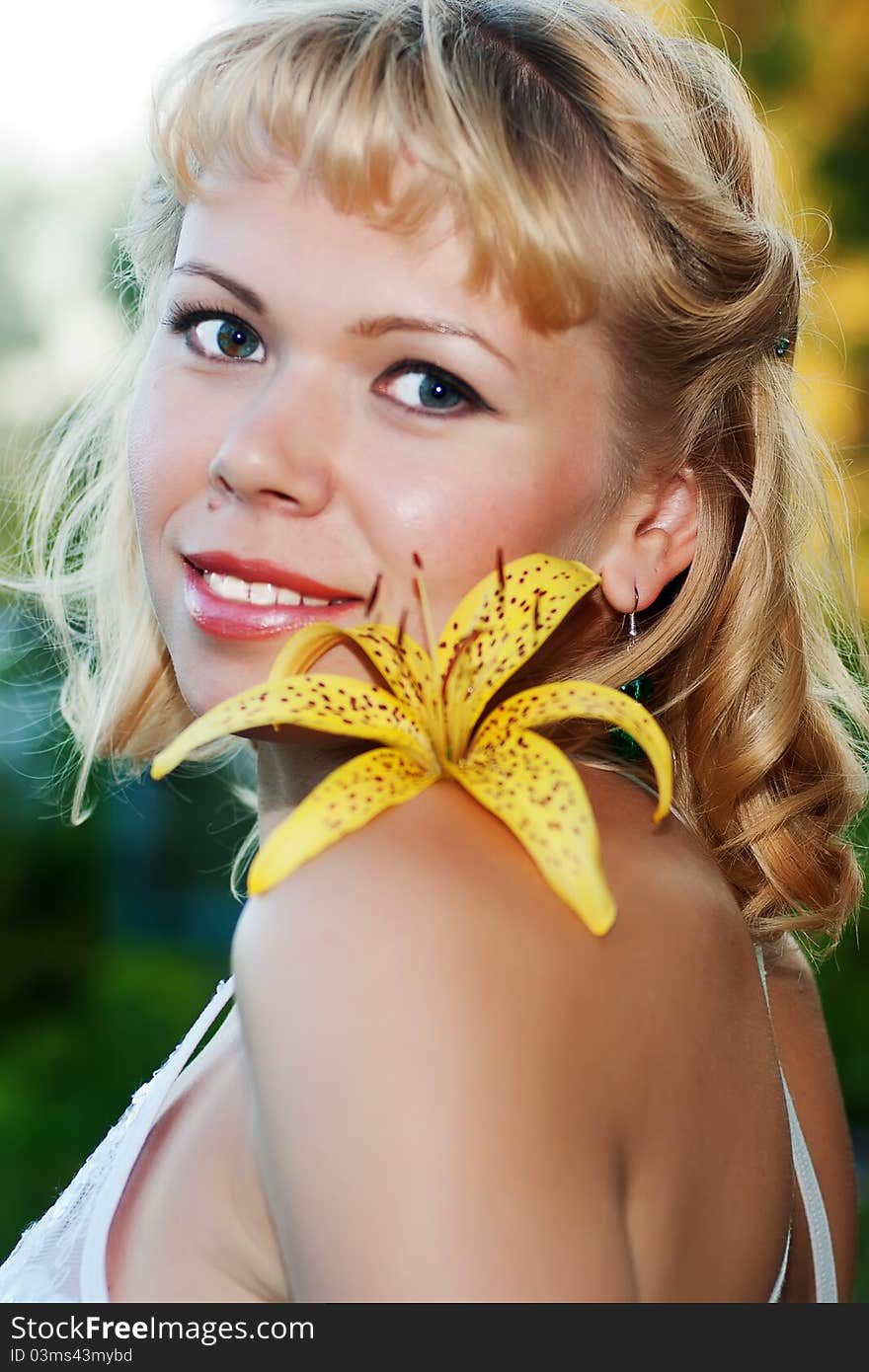 Smiling nice woman with yellow lily on shoulder