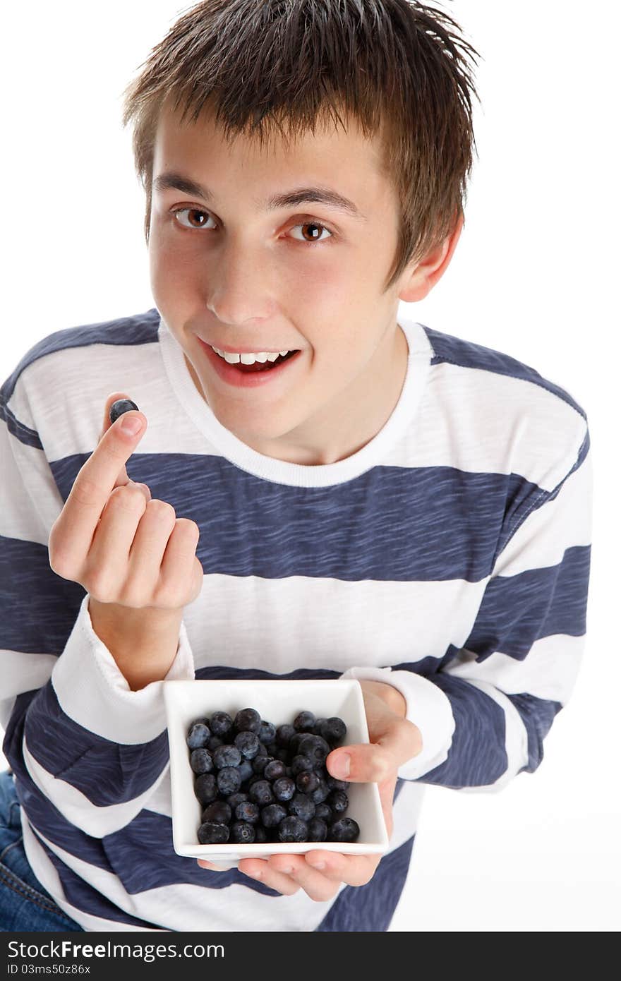 A boy holding a single blueberry in his fingers and smiling, while holding a small bowl filled with the delicious blueberries. A boy holding a single blueberry in his fingers and smiling, while holding a small bowl filled with the delicious blueberries.