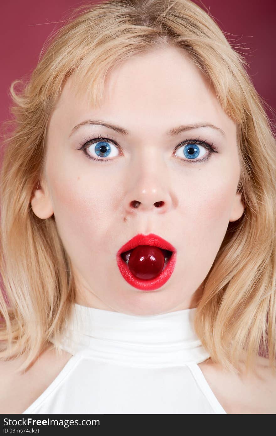 Surprised woman with cherry  in her mouth