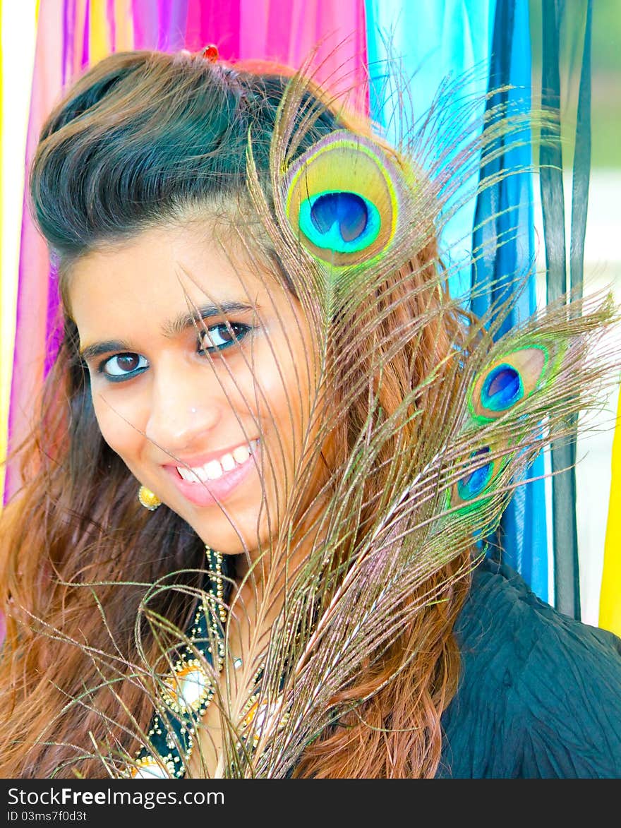 Young Pakistani model posing on a colorful background with peacock feathers. Young Pakistani model posing on a colorful background with peacock feathers