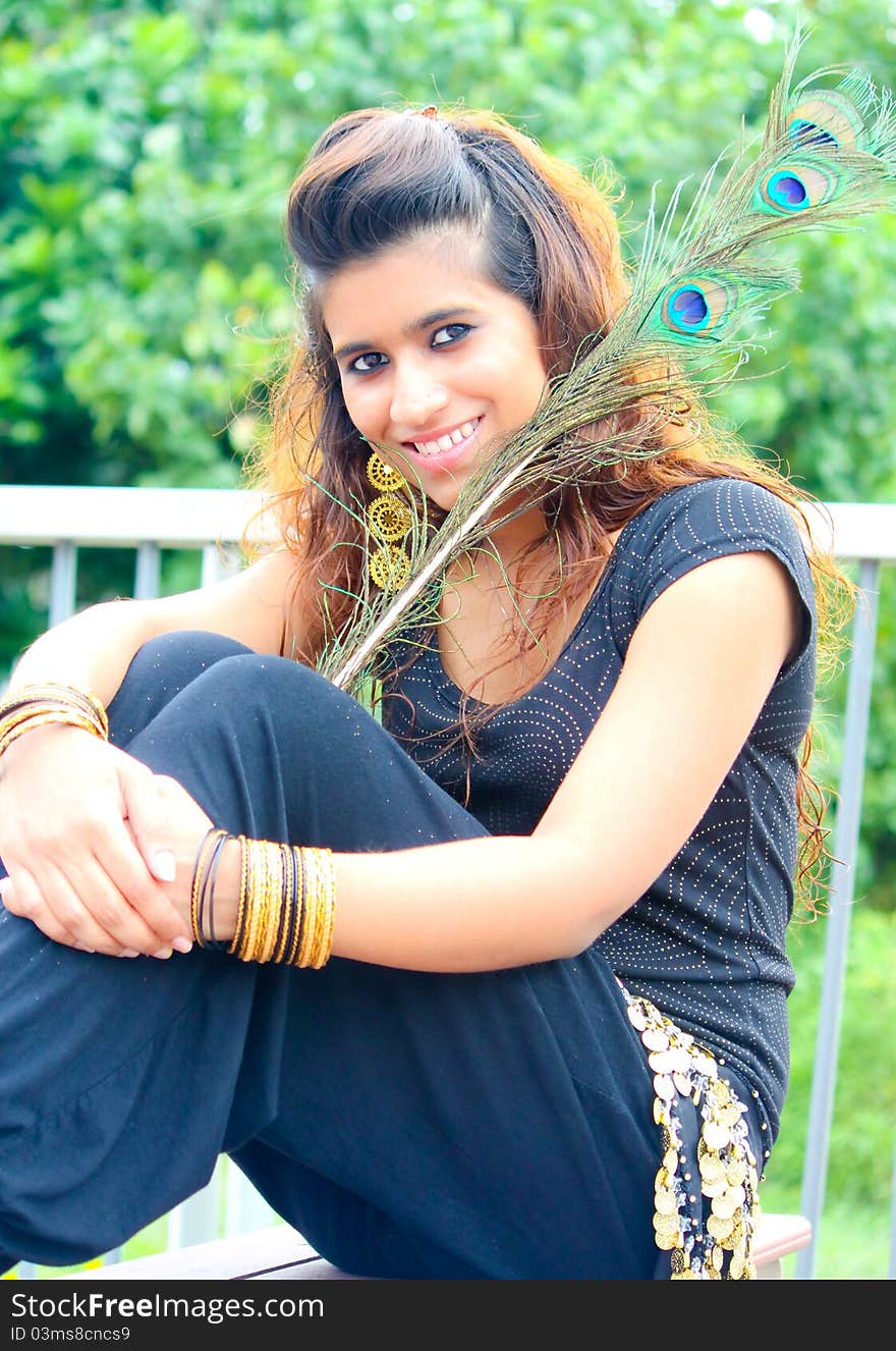 A young model posing with traditional indian peacock feathers in the outdoors. A young model posing with traditional indian peacock feathers in the outdoors