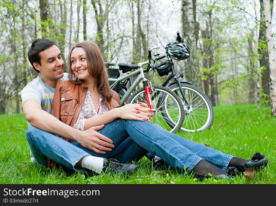 Young couple resting in a park, bicycles on background