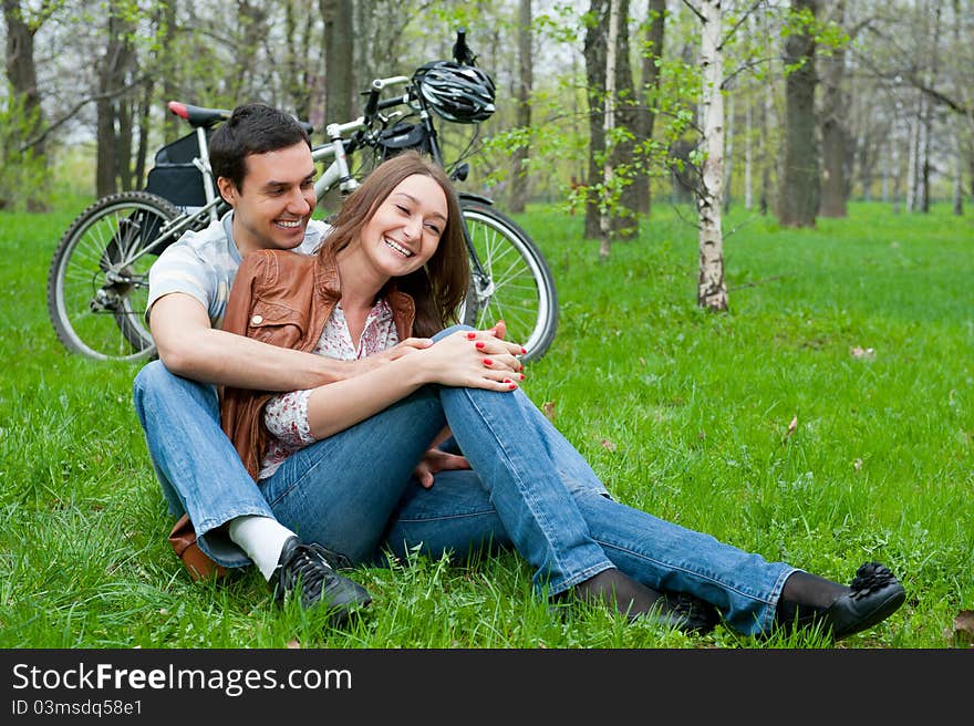 Young couple resting in a park, bicycles on background