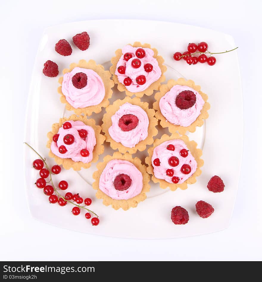 Tartlets with whipped cream and fruits - raspberries and redcurrants - on a plate