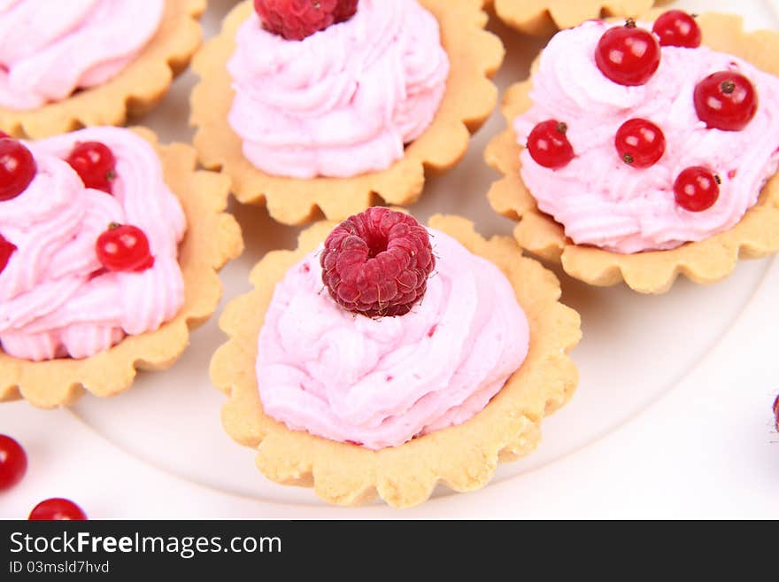 Tartlets with whipped cream and fruits - raspberries and redcurrants - on a plate