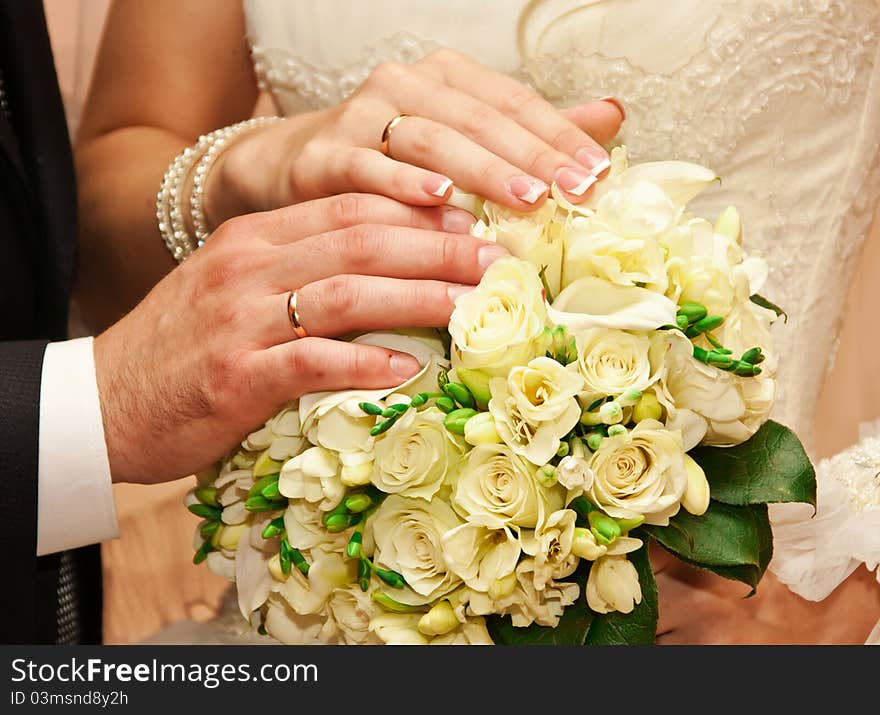 Hands on a bouquet of newly-weds in the registry office. Hands on a bouquet of newly-weds in the registry office