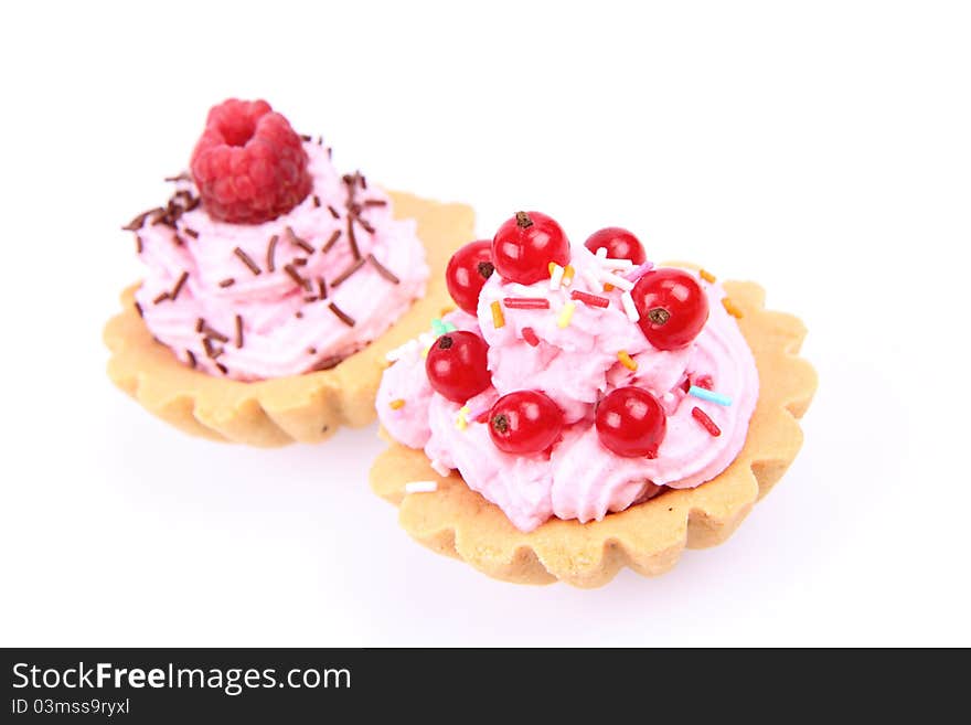 Tartlets with whipped cream, red currants, raspberry and sprinkles on a white background