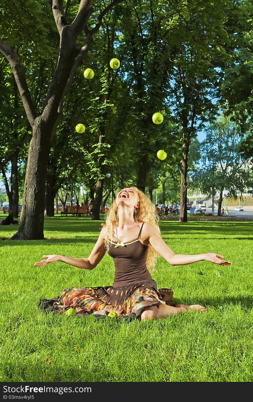 Portrait of young laughing girl throwing up green apples