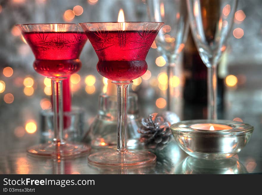 Close-up of glasses with red wine,candle light and twinkle lights on background. Close-up of glasses with red wine,candle light and twinkle lights on background.