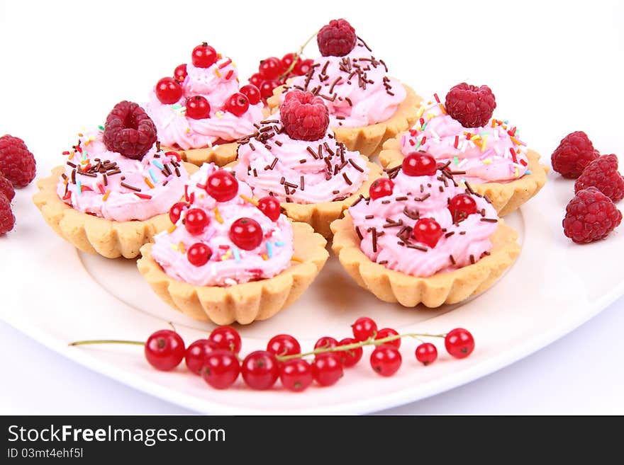 Tartlets with whipped cream and fruits - raspberries and redcurrants - on a plate