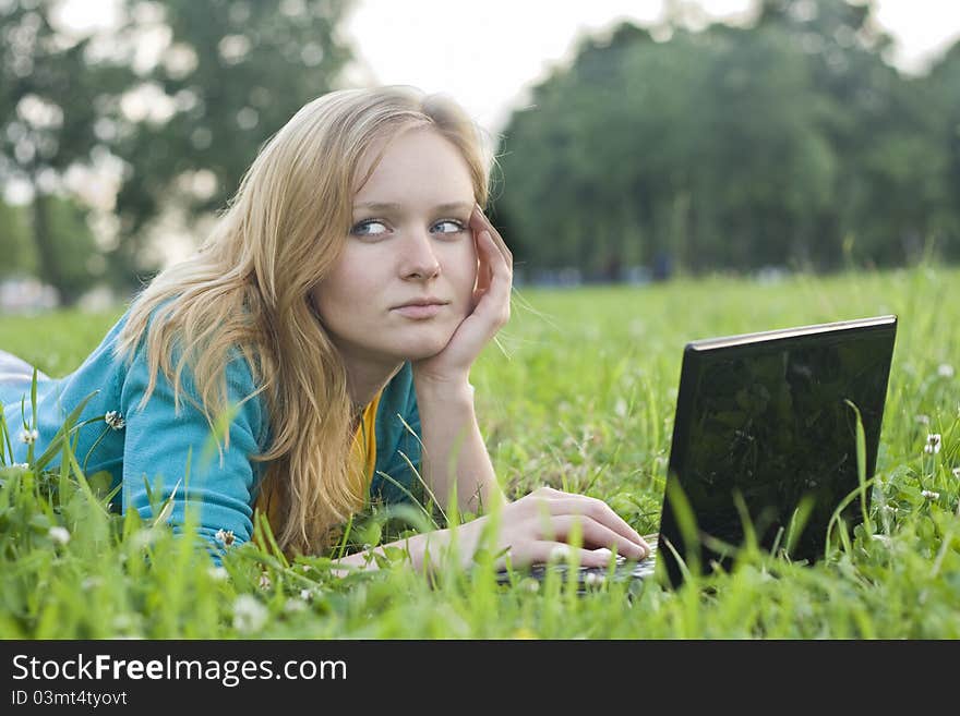 Portrait of pretty woman with laptop on the green grass