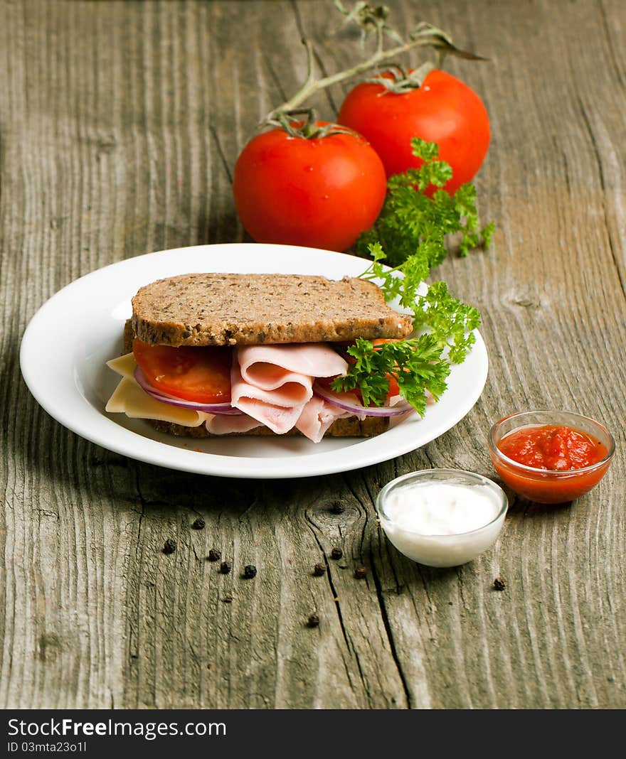 Fresh sandwich with cheese, ham on white plate and tow kind of sauces on old wooden table. Fresh sandwich with cheese, ham on white plate and tow kind of sauces on old wooden table