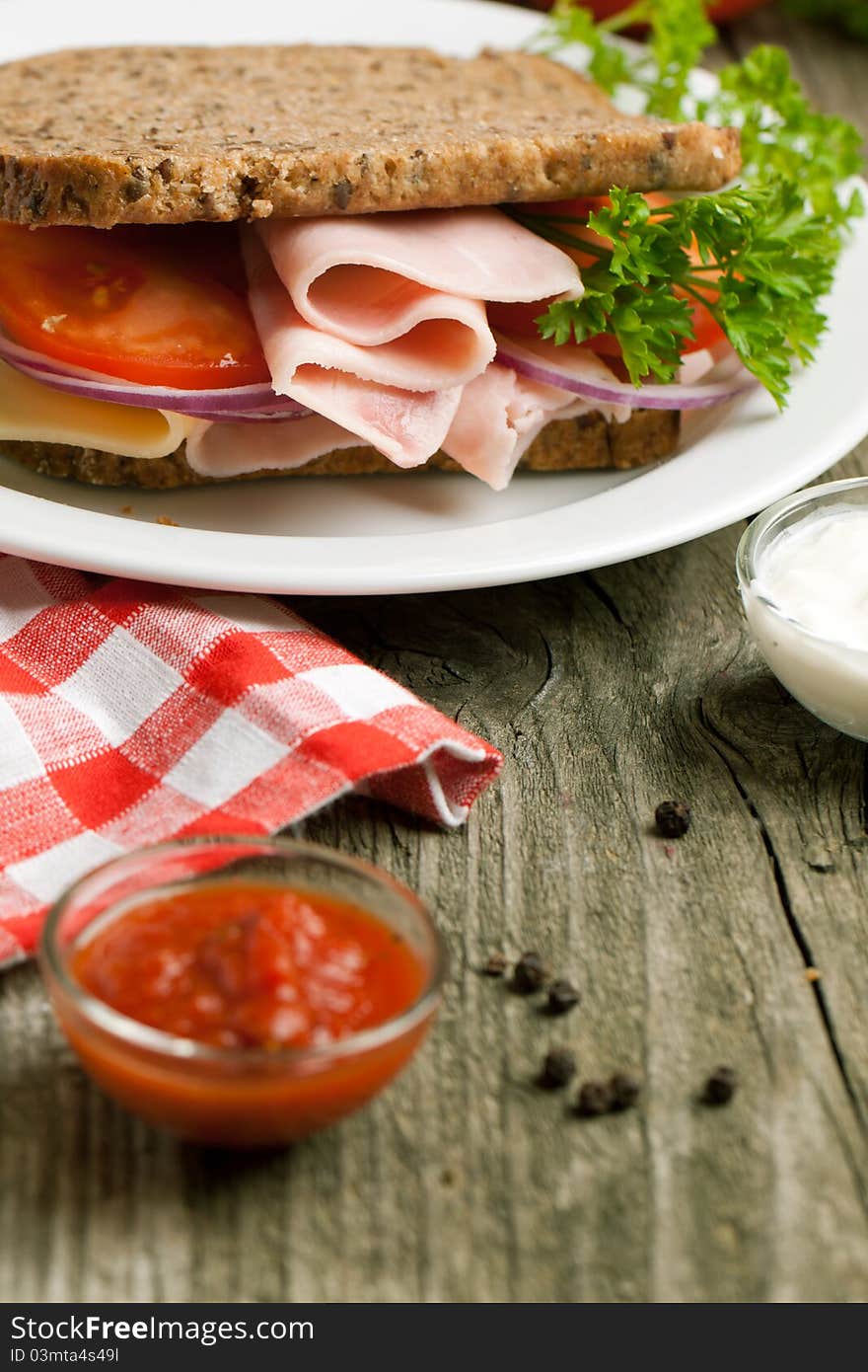 Fresh sandwich with cheese, ham and ketchup on old wooden table. Fresh sandwich with cheese, ham and ketchup on old wooden table