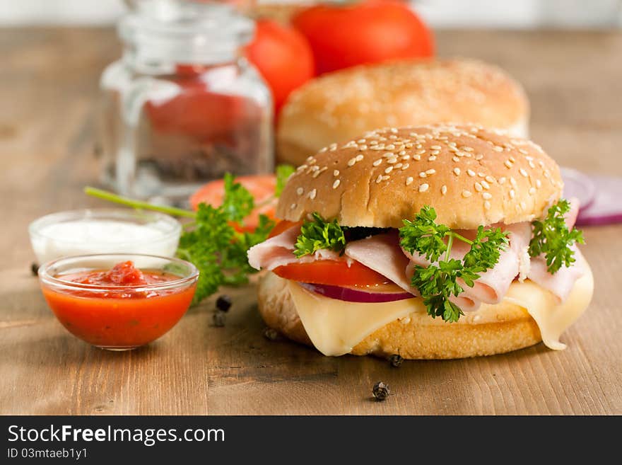 Fresh sandwich with cheese, ham and tomato and tow kind of sauces on wooden table. Fresh sandwich with cheese, ham and tomato and tow kind of sauces on wooden table