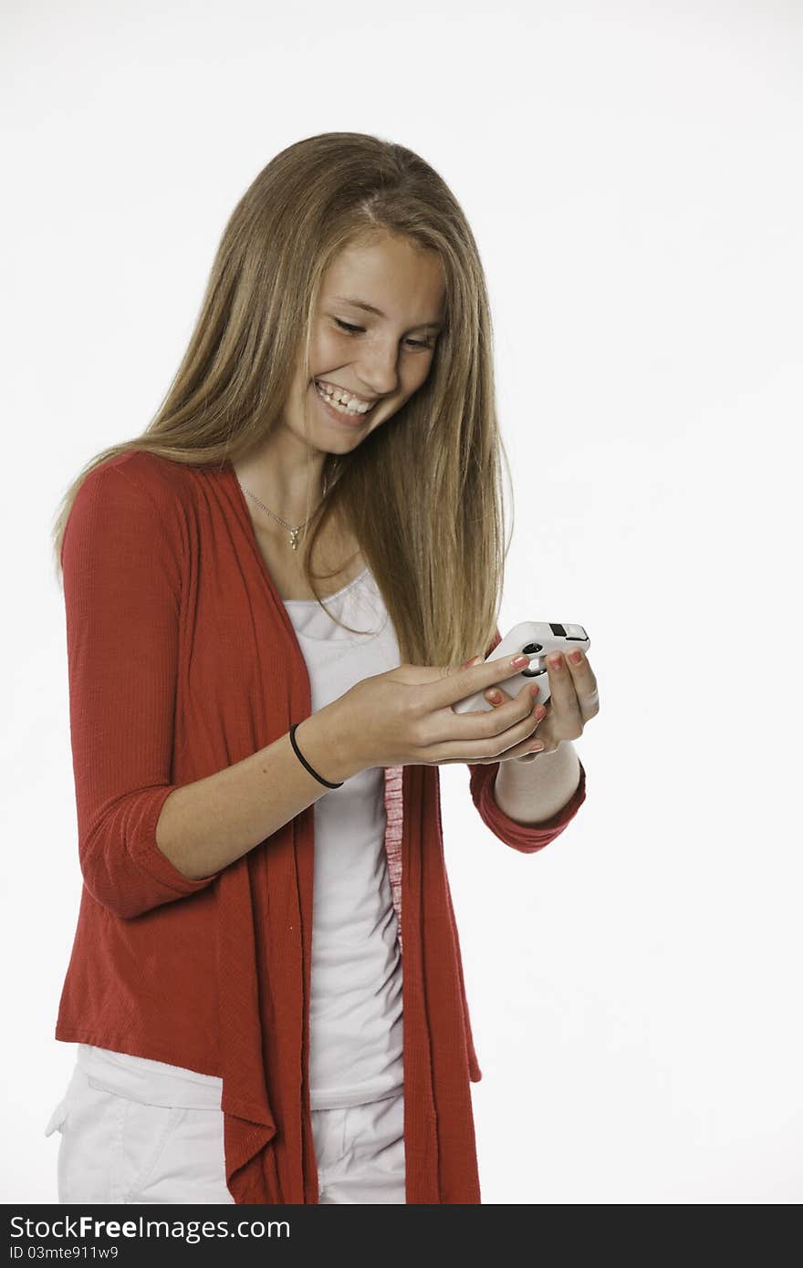 A laughing teenage female girl texting on a cell phone against a white background. A laughing teenage female girl texting on a cell phone against a white background.