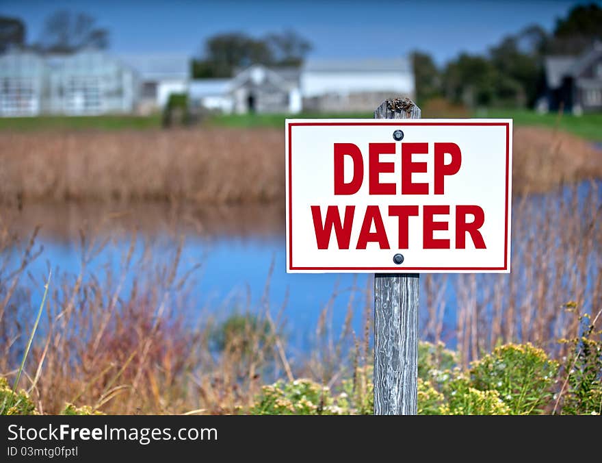 Sign near a body of water warning of deep water.