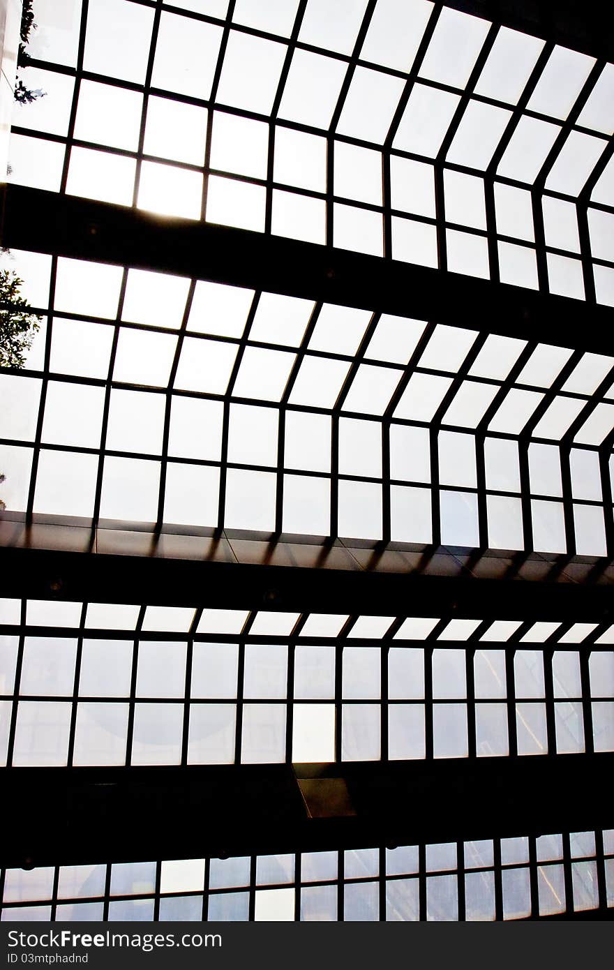 Modern glass ceiling with blue sky and sun