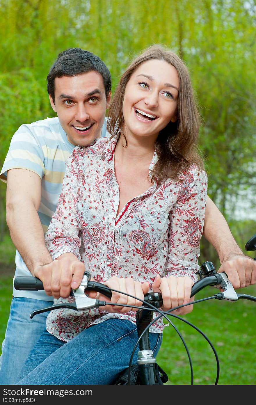 Happy young couple riding bicycle in a park