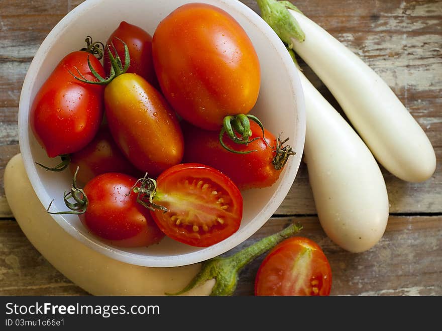 Fresh Roma and Juliet tomatoes picked fresh from the garden. Organically grown mini-eggplants on the outside of the bowl of tomatoes. Fresh Roma and Juliet tomatoes picked fresh from the garden. Organically grown mini-eggplants on the outside of the bowl of tomatoes.