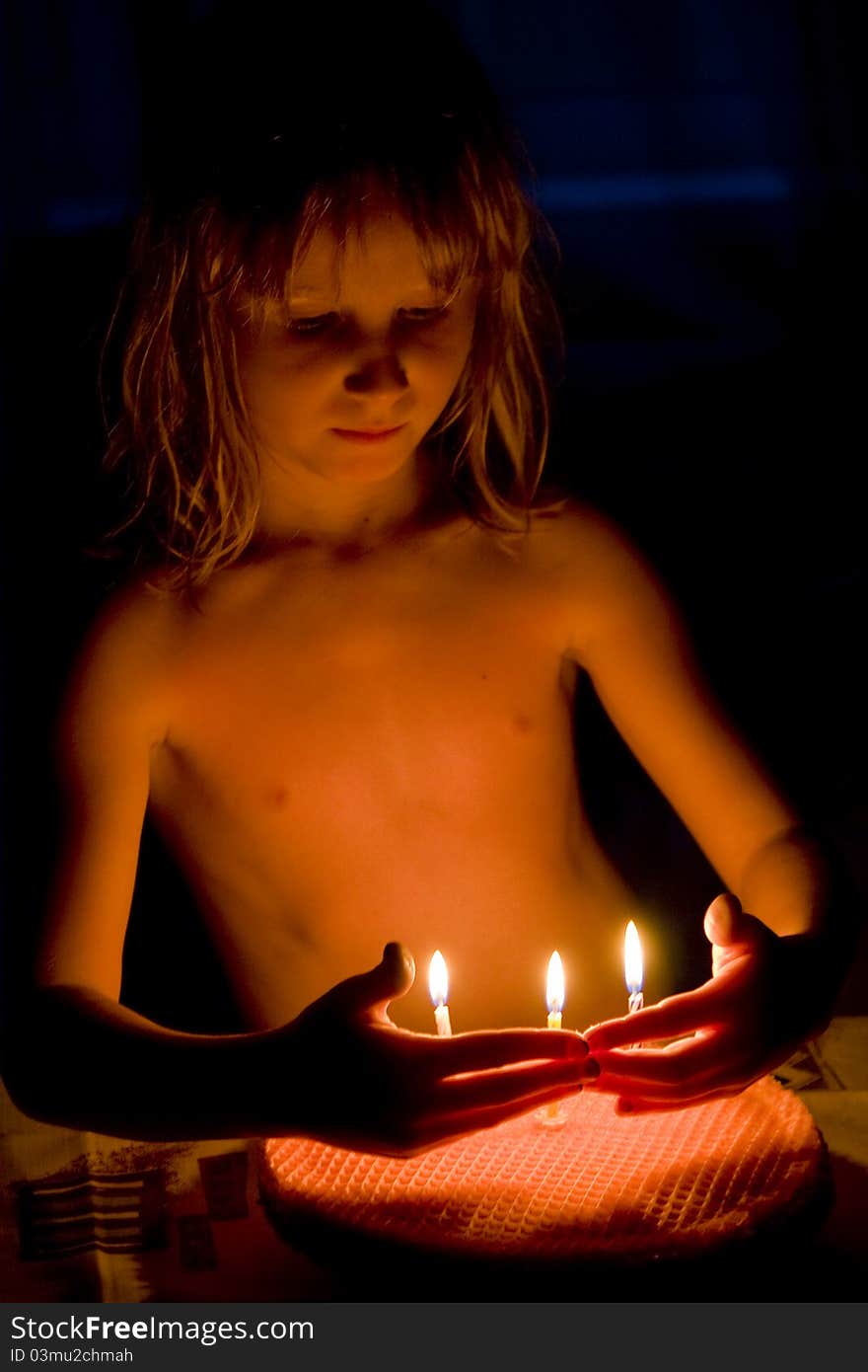 A girl looks at the cake with candles. A girl looks at the cake with candles