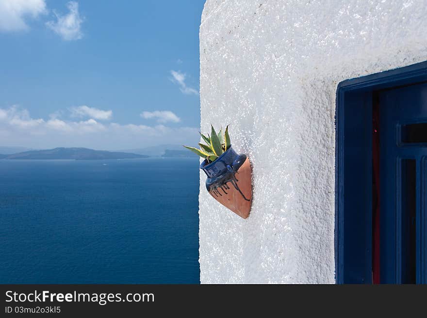 Ceramic flower pot on a white wall against a blue sea and clean blue sky. Ceramic flower pot on a white wall against a blue sea and clean blue sky