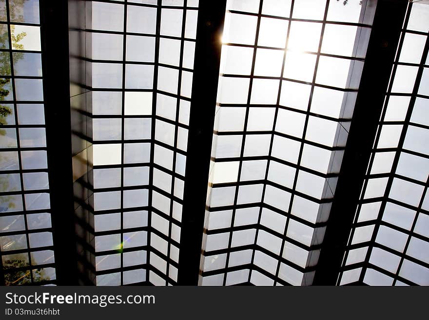 Modern glass ceiling with blue sky and sun