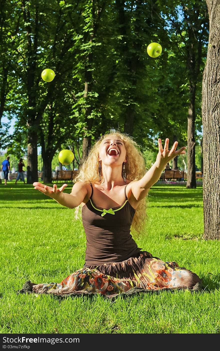 Portrait of young laughing girl throwing up green apples