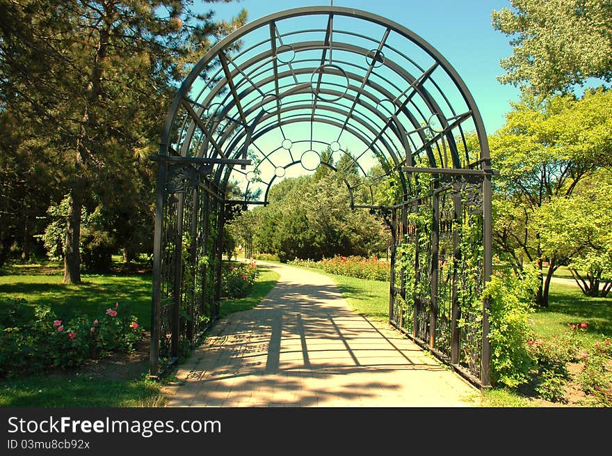 Decorative entrance leading to a garden pathwayDecorative black iron garden gate entrance to a peaceful botanical garden