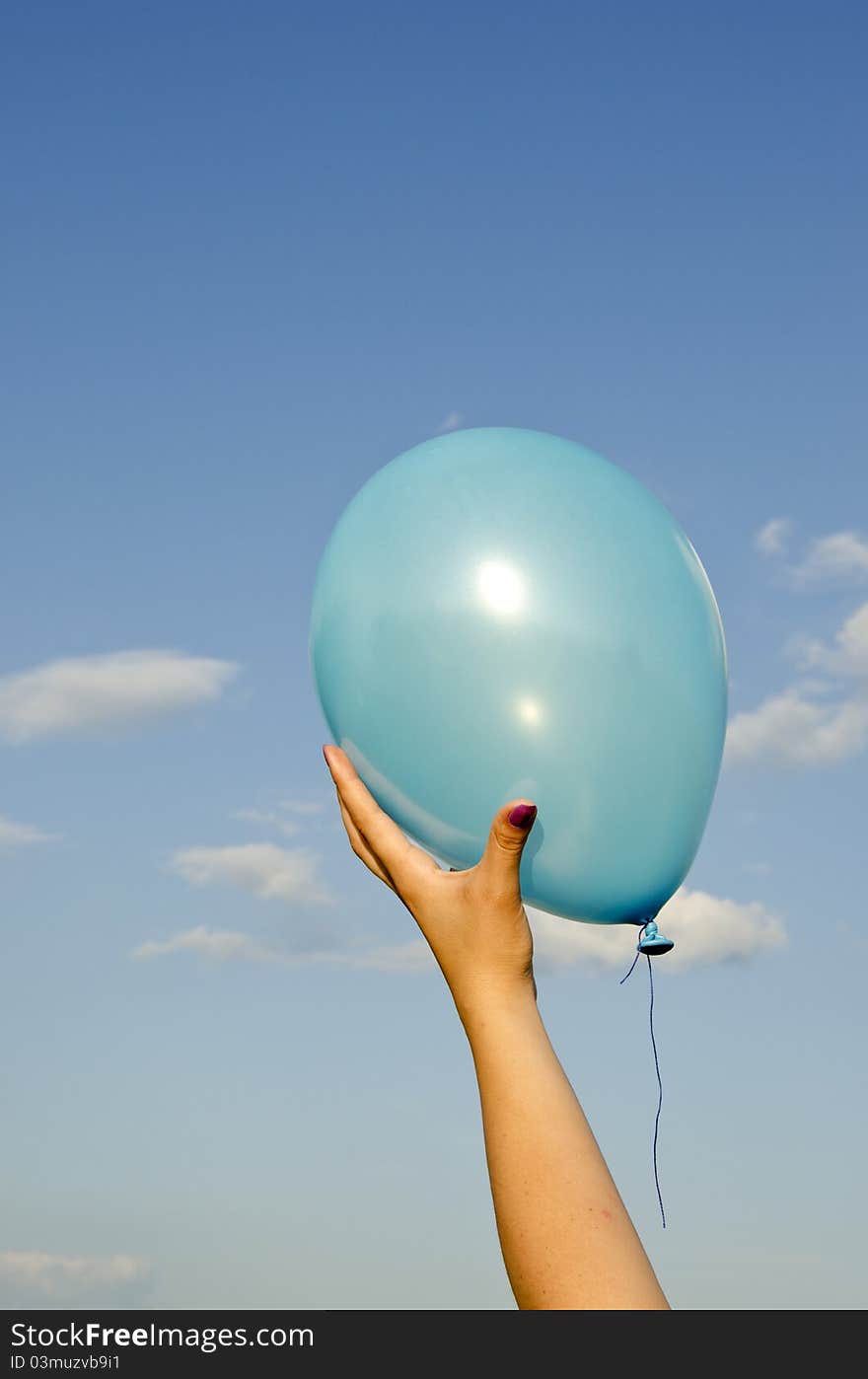 Girl hand holding azure balloon and sky