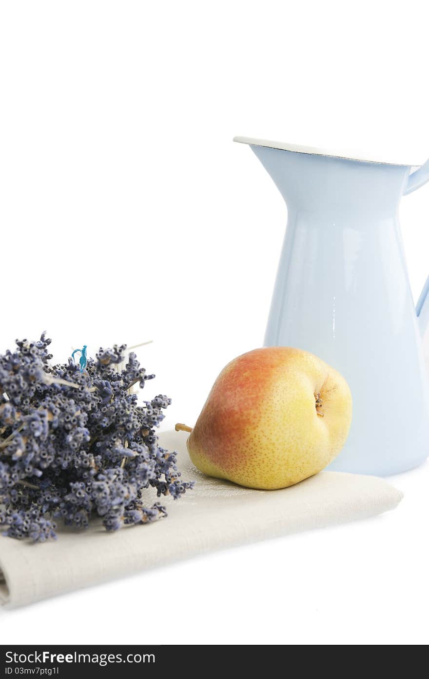 Metallic blue pitcher, pear and a bouquet of dried lavender in the linen napkin on a white background. Metallic blue pitcher, pear and a bouquet of dried lavender in the linen napkin on a white background