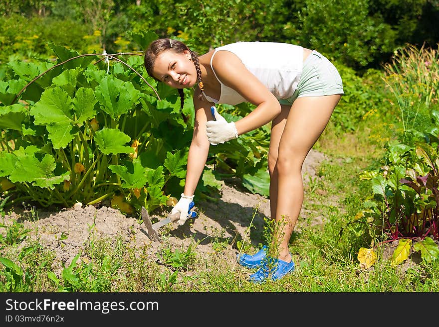 Young woman with hoe working in the garden bed