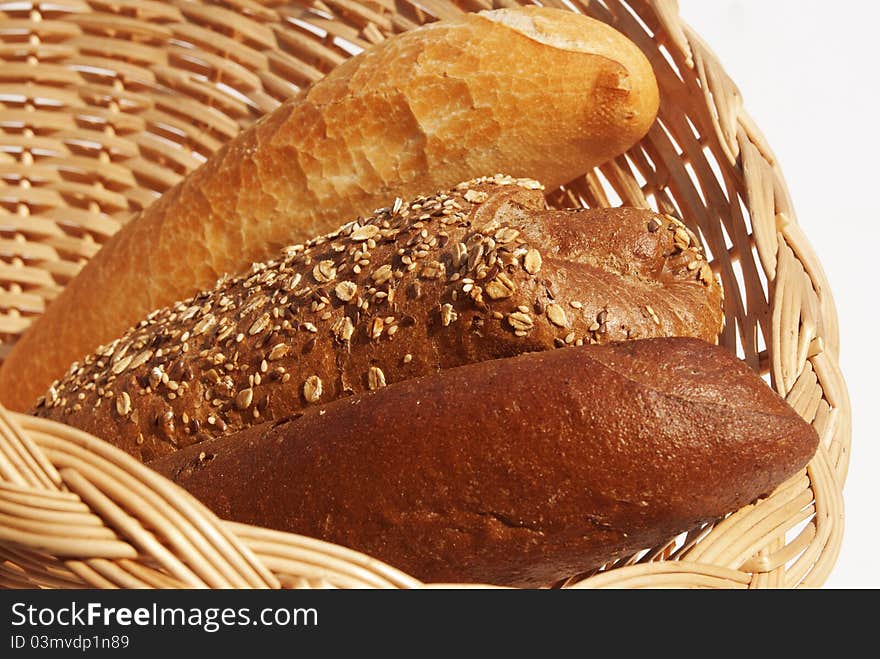 Long loaf of rye bread strewed by sunflower seeds on a white background