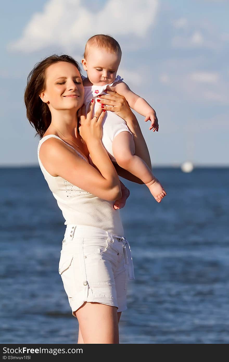 Happy mother and baby playing on beach