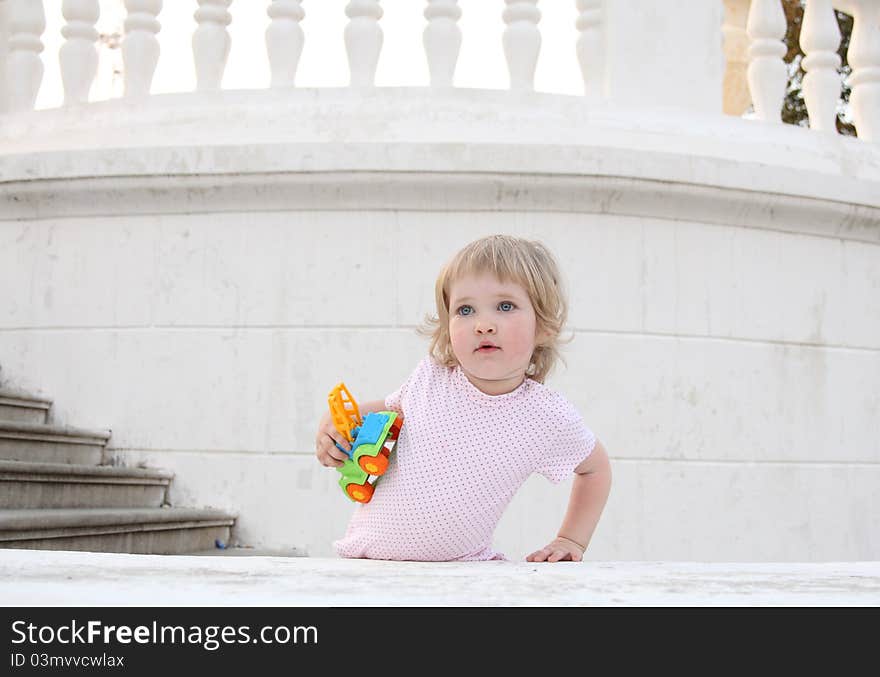 Baby girl with a toy stays on the stairs. Baby girl with a toy stays on the stairs