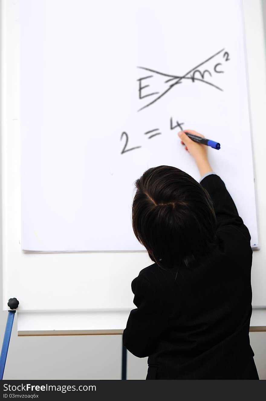 Genius little boy writting E=mc2 on the board, new formula instead, conceptual idea