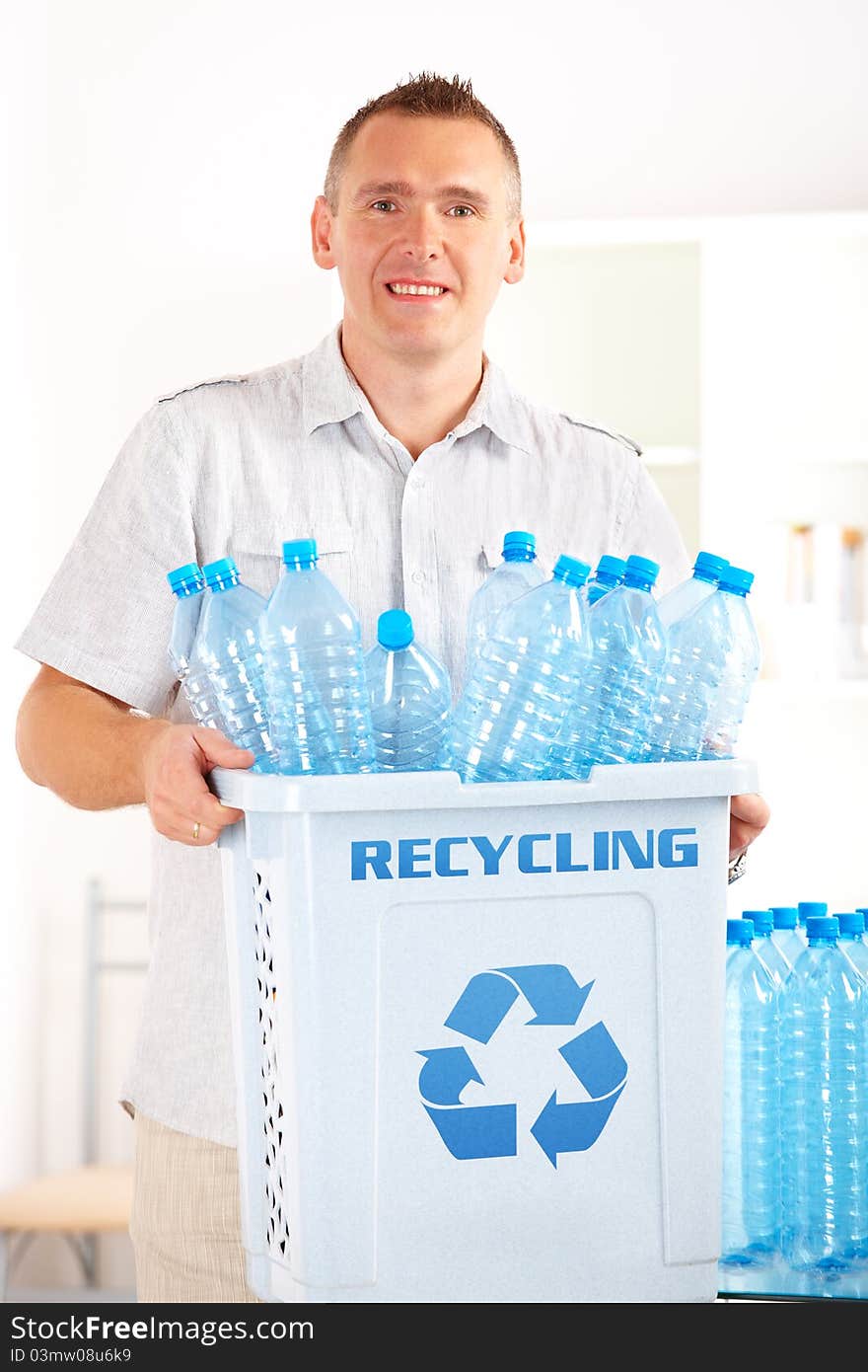 Happy man holding bin full of plastic blue bottles. Happy man holding bin full of plastic blue bottles