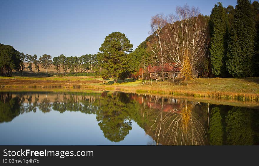 Long exposure image of a dam and autumn trees and small house