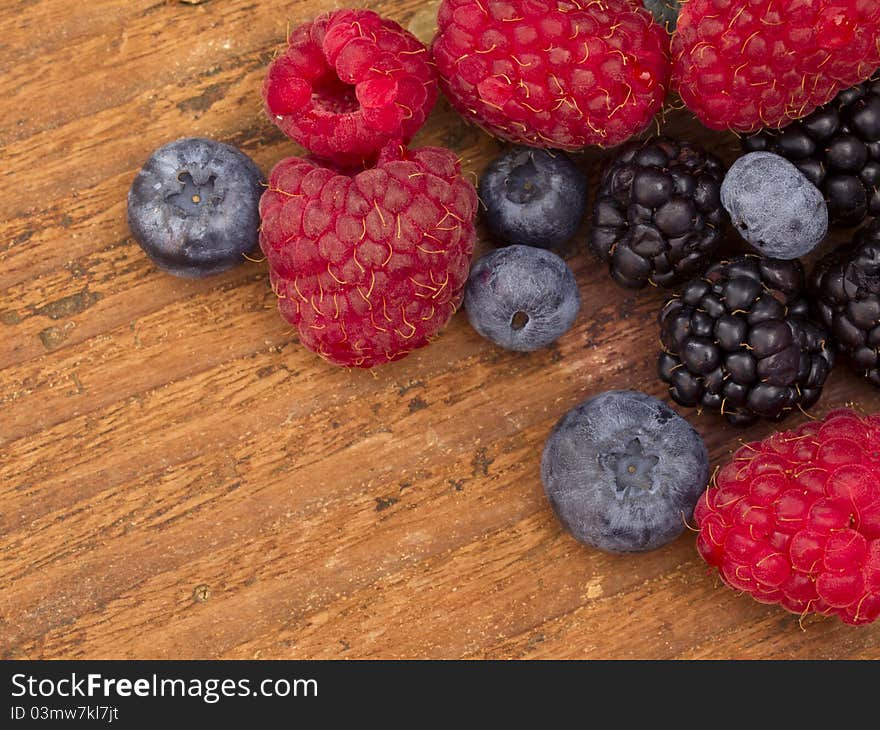 Raspberries, blueberries and blackberries on the wooden background. Raspberries, blueberries and blackberries on the wooden background