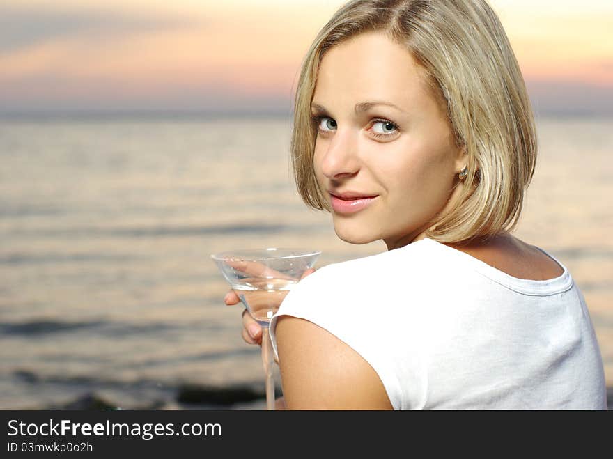 Portrait of a beautiful woman with cocktail on the sunset backgraund