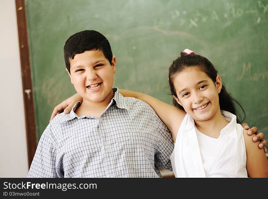 Two happy friends in front of green classroom board, school activities. Two happy friends in front of green classroom board, school activities