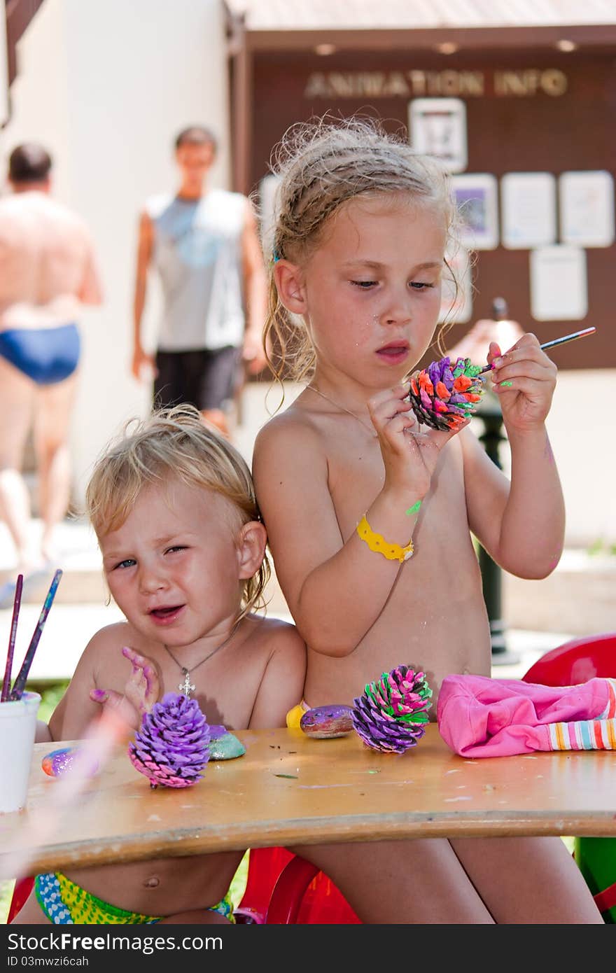 Beautiful girls painting beach pebbles and pine cones outdoor