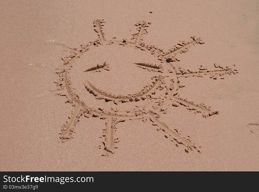 Smiling sun drawn on sand of a beach