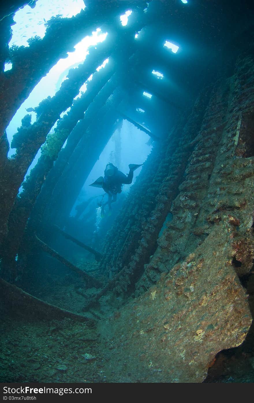 Scuba diver exploring the interior of a large shipwreck. Scuba diver exploring the interior of a large shipwreck