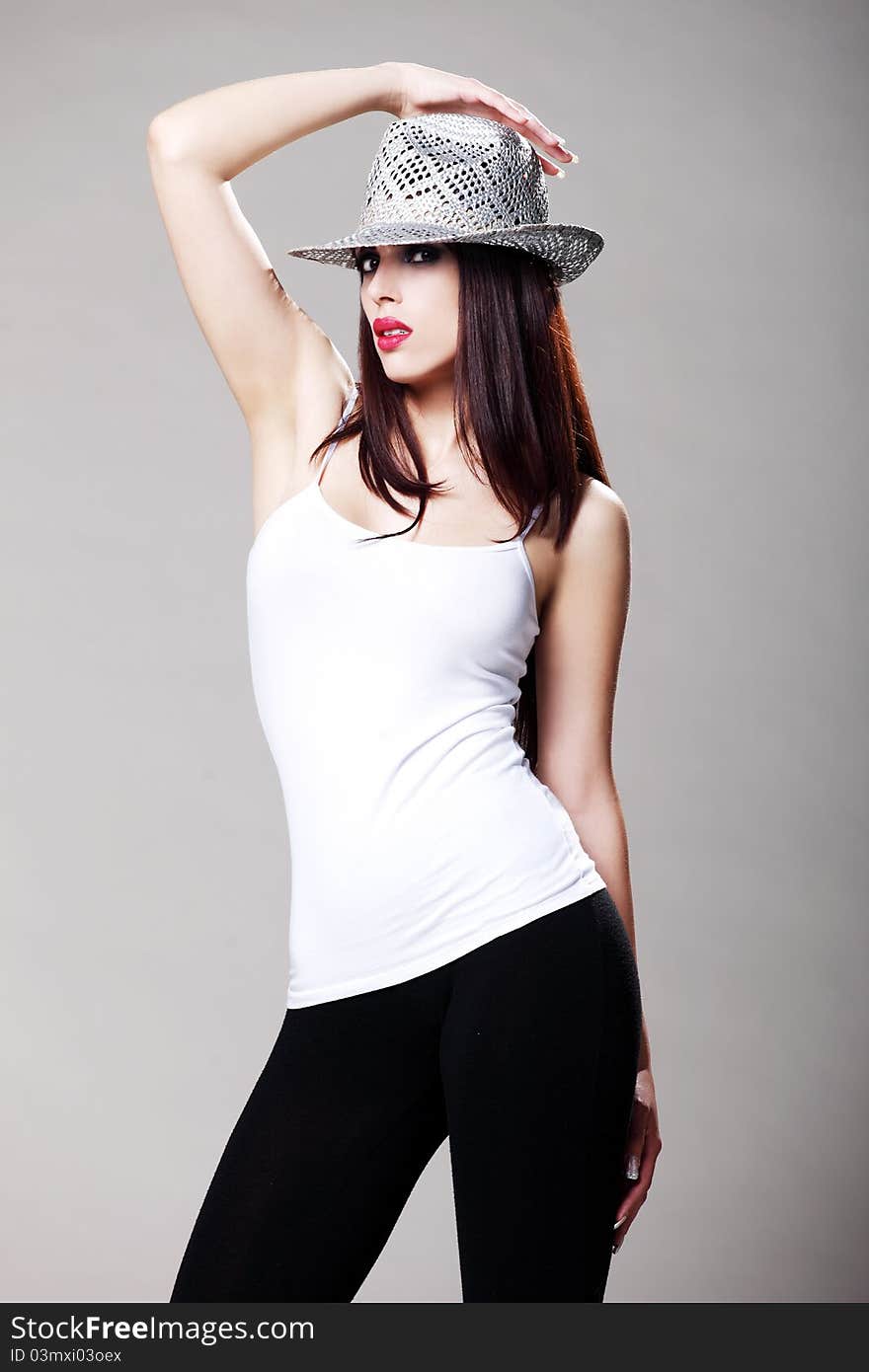 Attractive brunette in a white t shirt and black tights wearing a hat. Attractive brunette in a white t shirt and black tights wearing a hat